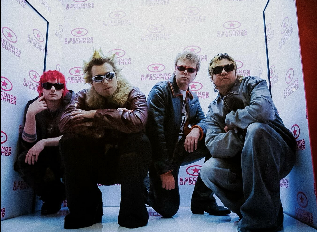 5sos posing inside a box wearing their "Everyone's a Star" album outfits.